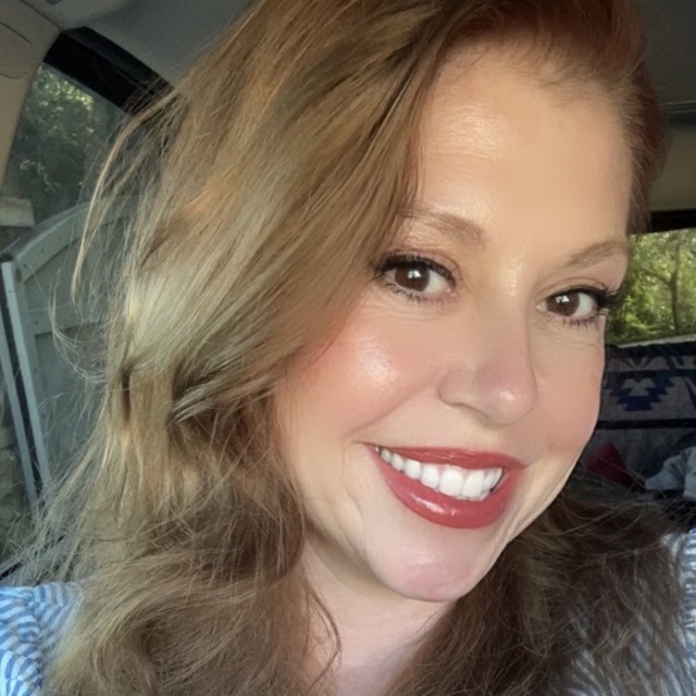 Crystal, founder of Serene & Clean, smiling, with long auburn hair and a blue striped shirt